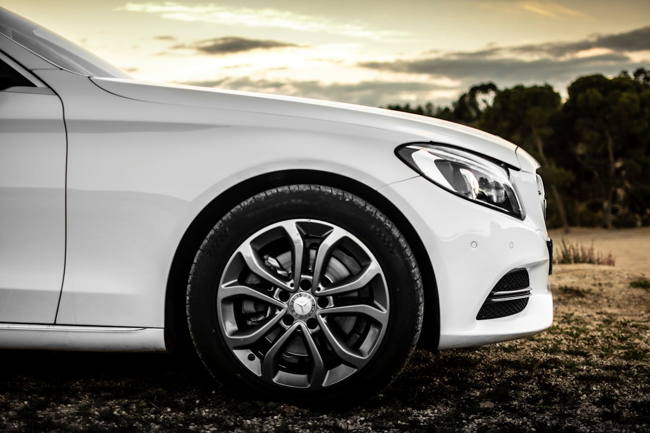 Close-up of a white car with stylish rims, captured outdoors in a serene setting.